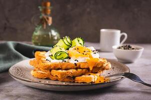 Toasts with cream cheese, cucumber, poached egg and sesame seeds on a plate on the table photo