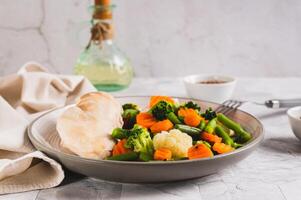 Mixed vegetables and steamed chicken breast on a plate on the table photo