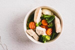 Close up of  soup with chicken, cauliflower, broccoli, carrots and green beans in a bowl top view photo