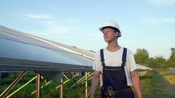 ingenieur wandelen in zonne- cel boerderij door veld- van zonne- panelen controle de panelen Bij zonne- energie installatie. zonne- cellen zullen worden een belangrijk hernieuwbaar energie van de toekomst video