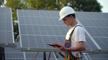 zonne- paneel technicus werken met zonne- panelen. ingenieur in een uniform met een tablet cheques zonne- panelen productiviteit. de toekomst is vandaag video