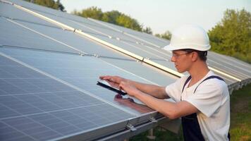 zonne- paneel technicus werken met zonne- panelen. ingenieur in een uniform met een tablet cheques zonne- panelen productiviteit. de groen energie concept video