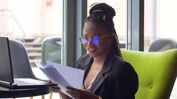 Afrikaanse Amerikaans meisje werken met documenten in cafe. einde van quarantaine video