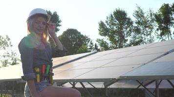 Female engineer in a white helmet is at the solar power station. The green energy concept video