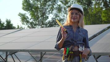 Female engineer in a white helmet spirit level is at the solar power station. Alternative energy concept video