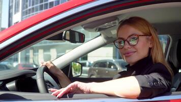 Attractive stylish woman with long hair in luxury car on a building background. Auto business, technology and people concept video