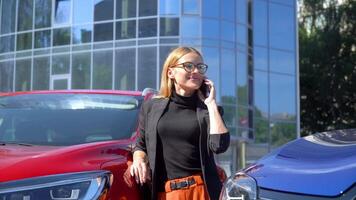 Successful businesswoman stand near a luxury cars while talking on smartphone near business center video