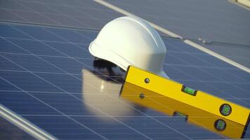 White hard hat and spirit level on solar panel. The concept of clean energy, green energy, renewable energy. Photovoltaic panel video