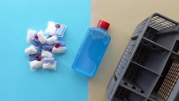 A stack of dishwasher tablets and a bottle of detergent on a blue background video