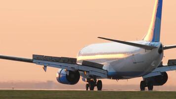 KAZAN, RUSSIA - AUGUST 05, 2022. Cinematic shot, Boeing 737 of Pobeda Airlines braking after landing. Aircraft arriving at sunset. Spoilers up. Airplane on a background of pink sky, sunset, dawn video