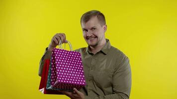 Man raising shopping bags, looking satisfied with purchase, enjoying discounts on Black Friday video