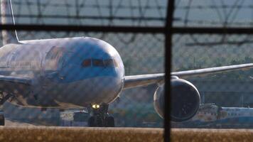 Phuket, Thailand - - Januar 27, 2023. boeing 787-8 Traumliner, g-tuic von tui fliegen rollen zu das Runway beim Phuket Flughafen. Flugzeug von hinten beleuchtet auf Rollbahn. Tafel hinter das Flughafen Zaun, Mittel Schuss video