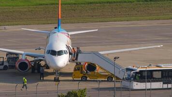 sotsji, Rusland - augustus 02, 2022. sukhoi superjet van azimut Aan de schort. vliegtuig onderhoud na landen. passagiers Uitgang via de trap. platform bus aan het wachten voor passagiers video