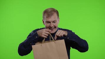 gioioso uomo mostrando nero Venerdì iscrizione a partire dal shopping borse, sorridente soddisfatto con Basso prezzi video
