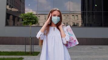 Teenager girl with multicolor shopping bags wearing protect mask. Black Friday during coronavirus video