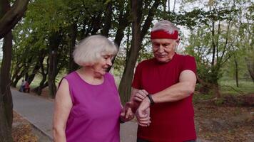 Mature family couple together after running using smart watch, tracking result of fitness workout video