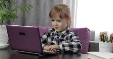 menina fazendo lições às casa usando digital computador portátil computador. distância Educação video