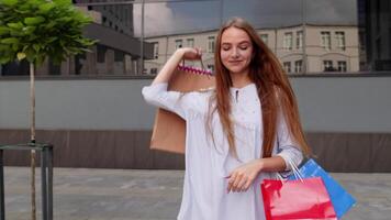 bonito niña caminando desde centrar centro comercial con compras bolsas, contento con compra en negro viernes video