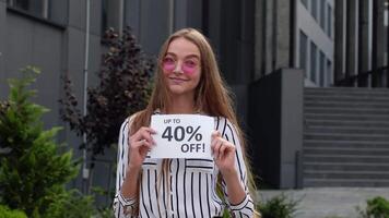 Cheerful girl showing Up To 40 percent Off text advertisement. Online shopping with low prices video