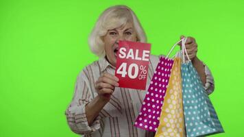 Cheerful grandmother with shopping bags showing Sale 40 percent Off banner text advertisement video