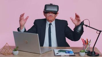 Senior businessman using headset helmet app to play simulation game, watching virtual reality video