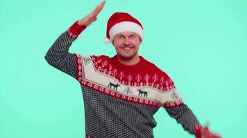 Mens in trui de kerstman Kerstmis hoed dansen modieus dans voor sociaal media voor de gek houden in de omgeving van hebben pret video