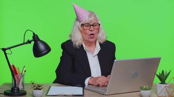 Sad upset lonely senior businesswoman celebrating birthday party alone, holds cake at green office video