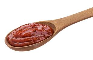 Ketchup in wooden spoon isolated on white photo