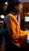 Vertical Video African american IT student practicing coding or programming exercises, learning hardware language and system debugging. Young woman studying database script on html window. Camera B.