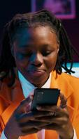 Vertical Video College student doing her homework at laptop and texting on phone, enjoying school break to check social media apps. Girl researching for assignments and using smartphone. Camera A.