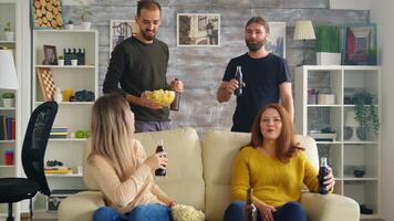 jovem homem ofertas menina salgadinhos enquanto assistindo uma Combine em televisão e bebendo cerveja. video