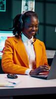 Vertical Video Student listening to music while she writes her essays at home, enjoying groovy tunes on headphones. Young woman creating a relaxing atmosphere to finish homework and tasks. Camera B.