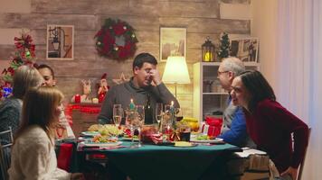 Big happy family exchanging presents at christmas reunion. Winter holidays. Traditional festive christmas dinner in multigenerational family. Enjoying xmas meal feast in decorated room. Big family reunion video