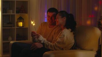 romántico joven Pareja participación mano fuegos artificiales celebrando Navidad. celebrando nuevo año víspera y Navidad noche, juntos amor celebracion bengala y hogar en antecedentes video