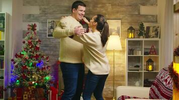 Happy young woman dancing with her husband celebrating christmas. Xmas holiday together celebration of love, fun dance romantic lifestyle in decorated room with fireplace in background video