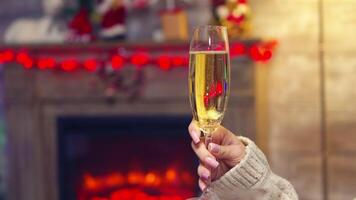 Close up of couple clinking sparkling champagne celebrating christmas. Christmas tree celebration, new year eve with sparkling wine in cozy home with fireplace. Xmas emotions holiday and family video