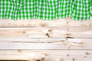 Green tablecloth on wooden table, top view photo