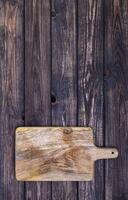 Old cutting board on dark wooden table. Top view. Copy space photo