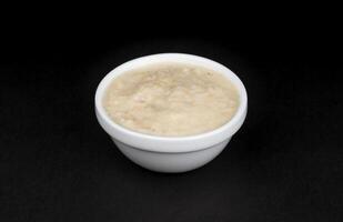 Horseradish sauce in bowl isolated on black background photo