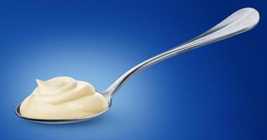 Sour cream in spoon isolated on blue background photo