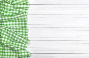 Green checkered tablecloth on wooden table, top view photo