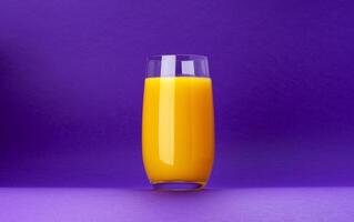 Glass of orange juice isolated on violet background with copy space photo
