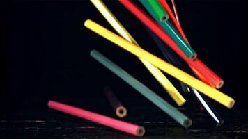 A pile of colored pencils falls on the table. On a black background. Filmed is slow motion 1000 fps. High quality FullHD footage video