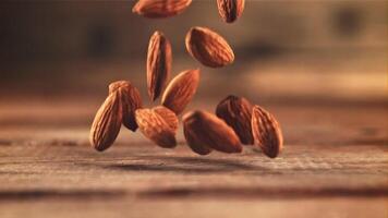 Almonds fall on the table. On a wooden background. Filmed on a high-speed camera at 1000 fps. High quality FullHD footage video