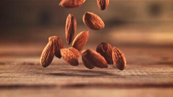 Almonds fall on the table. On a wooden background. Filmed on a high-speed camera at 1000 fps. High quality FullHD footage video