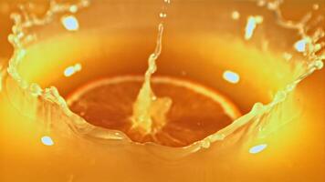 A piece of fresh orange falls into the orange juice with splashes. Macro background.Filmed on a high-speed camera at 1000 fps. video