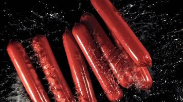 Sausages fall on the water with splashes. On a black background. Filmed on a high-speed camera at 1000 fps. High quality FullHD footage video