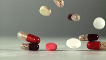 Different types of pills and capsules fall on the table. On a gray background. Filmed on a high-speed camera at 1000 fps. video