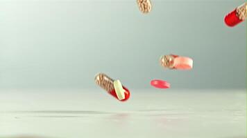 Different types of pills fall on the table. On a white background.Filmed on a high-speed camera at 1000 fps. video