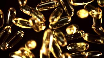 Omega 3 capsules rotate in flight. On a black background. Filmed is slow motion 1000 fps. video